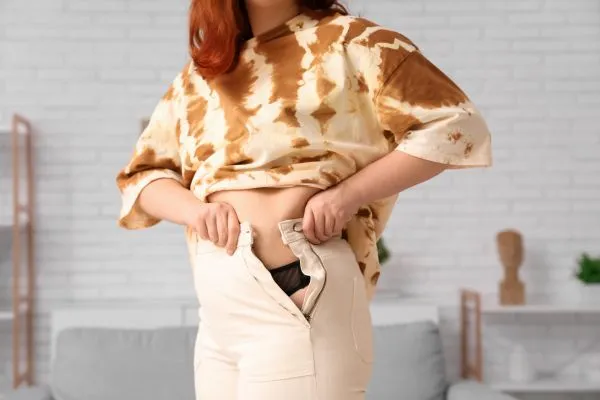 Image of woman trying to do her trousers up after pregnancy weight gain Northwood